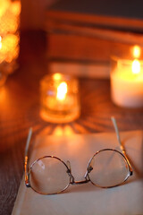 Vintage books, reading glasses, e-reader, cup of tea or coffeee, glass of orange juice, cookies, flowers and scented candles on the table. Hygge at home. Selective focus.