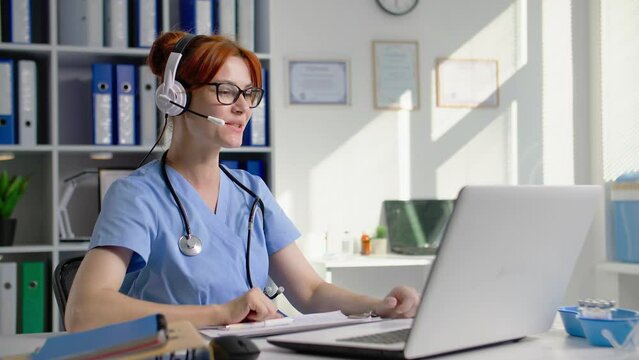 online medicine, a young female doctor communicates via video conference on laptop using a headset, tells the test results while sitting in a hospital office