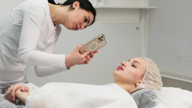 Medical office, a female doctor takes a photograph of a patient on the phone, after injections of hyaluronic acid, facial correction and cosmetology.