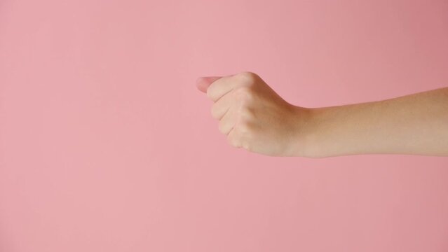 Vertical video of female hand pointing on you and come closer, isolated on pink color background with copy space for advertisement. Body language concept. With place for text or promotional content