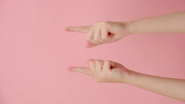 Vertical video of female hands pointing up demonstrating blank area on pink empty space commercial background loop. Recommending sign. With place for text or image. Special offer concept