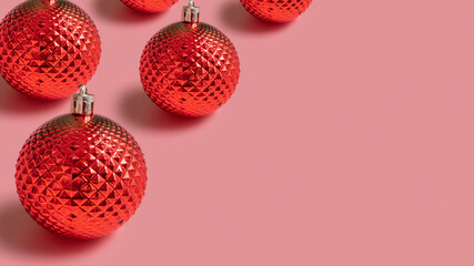 Christmas baubles on pink background with copy space.
