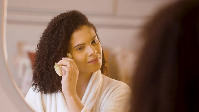 Beauty Unveiled: Woman Nurtures Skin with Jade Massager. Wellness, Skincare, and Self-Care Ritual in a Relaxing Home Ambiance.