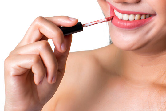 Cropped image of a woman applying red lip gloss on a white background.