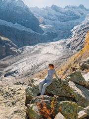 Woman in the mountains. Mountain with glacier and tourist sitting on stone