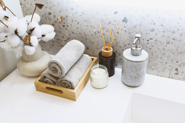 modern bathroom interior details with grey stone walls, hand towels, liquid soap, candle and bouquet.