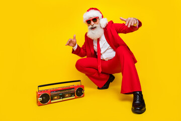 Fototapeta na wymiar Full length photo of funky cool man pensioner dressed red suit santa hat listening boom box songs isolated yellow color background