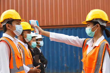 asian man workers wearing face mask checking fever by digital thermometer before entering the work...