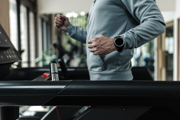 A man wearing smart watch and running on track treadmill, exercise fitness. Fitness, gym, workout...