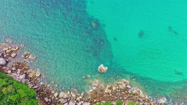 aerial view waves crashing on the rock beside the beach..white bubble waves in turquoise sea on the rock. .creative nature and travel concept. .