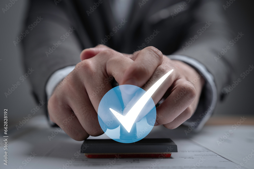 Poster Businessman holding rubber stamp with white correct sign or tick mark for document , project approve and accept verification code concept.