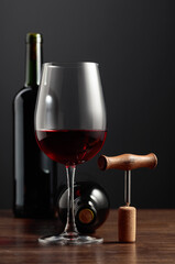 Red wine and corkscrew on a wooden table.