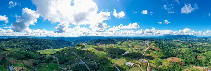 Panoramic view of Powerful wind turbine farm for pure energy production on beautiful clear blue sky with white clouds and wind farm background. Wind turbines for the generation of electricity