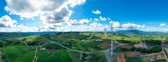 Panoramic view of Powerful wind turbine farm for pure energy production on beautiful clear blue sky with white clouds and wind farm background. Wind turbines for the generation of electricity - obrazy, fototapety, plakaty