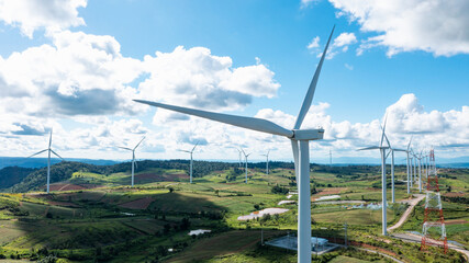 Aerial view of Powerful wind turbine farm for pure energy production on beautiful clear blue sky with white clouds and wind farm background. Wind turbines for the generation of electricity