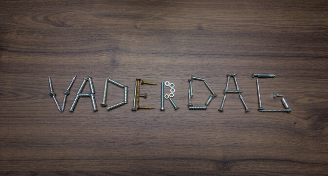 Dutch text Vaderdag made of screws on a dark wooden background, Father's Day concept