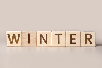 The Word Winter on wooden cubes on a beige neutral studio background. Copy Space. Written. Text...