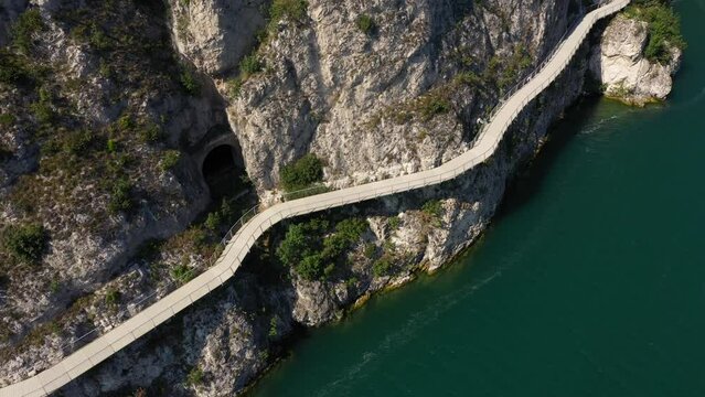 Section of the longest pedestrian and cycle path in Europe, 4K aerial view. Garda bike path. Alley Limone sul Garda. Garda bicycle and pedestrian path suspended above the lake.