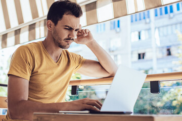 Confused male freelancer in casual wear making mistake with application on laptop at cafe