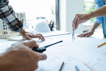 Engineers looking and discussing over blueprints on desk.
