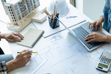Engineers looking and discussing over blueprints on desk.