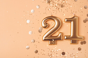 21 years celebration. Greeting banner. Gold candles in the form of number twenty one on peach background with confetti.