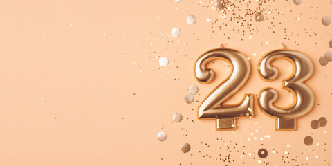23 years celebration. Greeting banner. Gold candles in the form of number twenty three on peach background with confetti.