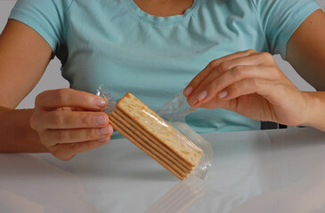 Woman opening cracker soda pack on kitchen table.