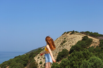 Naklejka premium The girl runs through the hills in the south, near the sea. The girl from the back. The girl's back. The view from the hight.