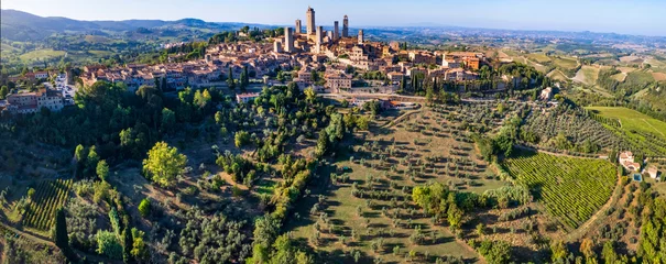 Poster San Gimignano - one of the most beautiful medieval towns in Tuscany, Italy. aerial drone panoramic view with green agricultures filelds and  Unesco heritage site. © Freesurf