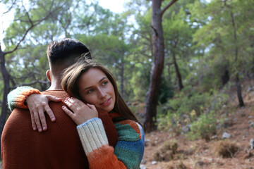 Young couple hiking in the woods. Hipster boyfriend and girlfriend hugging under the tree. Close up, copy space, forest background.