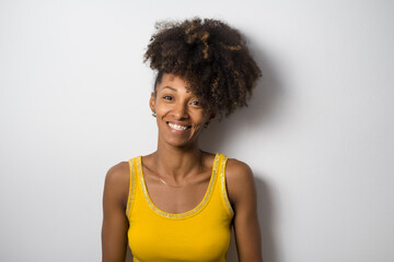 Portrait of a beautiful happy young afro hair style woman against white wall. Copy space background. Charming black female model.