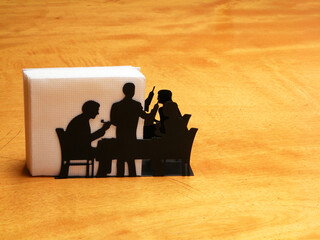 Black napkin holder with silhouettes of people at a dinner