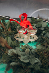 Two glasses of champagne in craft glass holders in the center of a Christmas wreath