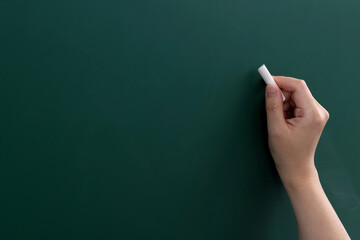 Hand holding chalk writing on chalkboard - obrazy, fototapety, plakaty