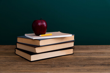 Red apple on book in front of the blackboard
