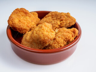 A round bowl of crispy fried chicken nuggets on a white background