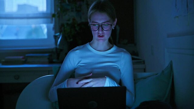 Young teenage female talking online using laptop, in evening