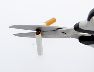 Scissors cut cigarette on white background