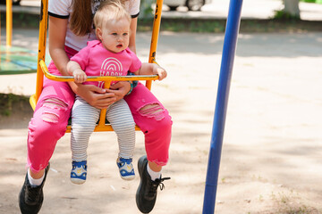 Girls sisters ride on a swing - a baby girl and a teenager.