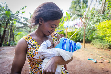 An African mother feeds her newborn son from her breast in the village