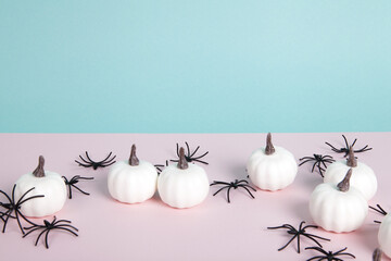 mini pumpkins surrounded by an infestation of spiders on a pink background against a horizon of blue sky