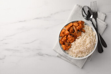 Bowl of delicious rice with meat and mushrooms served on white marble table, flat lay. Space for text
