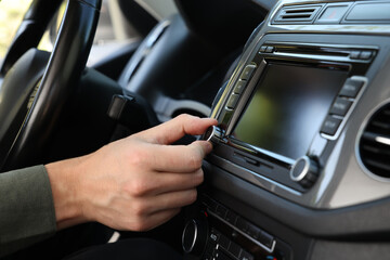 Listening to radio while driving. Man turning volume button on vehicle audio in car, closeup