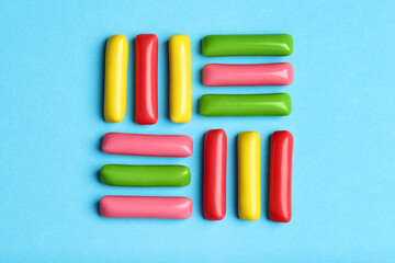 Many tasty bubble gums on light blue background, flat lay