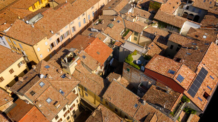 Aerial view of the sloping roofs of the houses in the historic center of Reggio Emilia, Italy. The orange color of traditional roofs predominates.