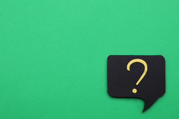 Paper speech bubble with question mark on green background, top view. Space for text