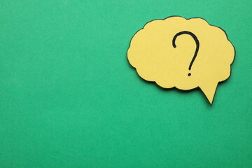 Paper speech bubble with question mark on green background, top view. Space for text