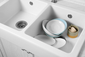 Clean tableware in white sink in kitchen