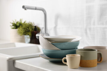 Clean tableware on light countertop near sink in kitchen